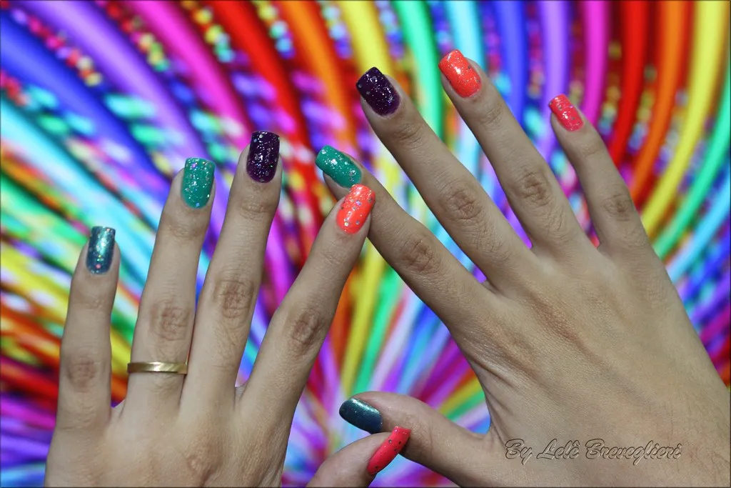 Manos con uñas multicolor con glitter sobre un fondo de espiral arcoíris
