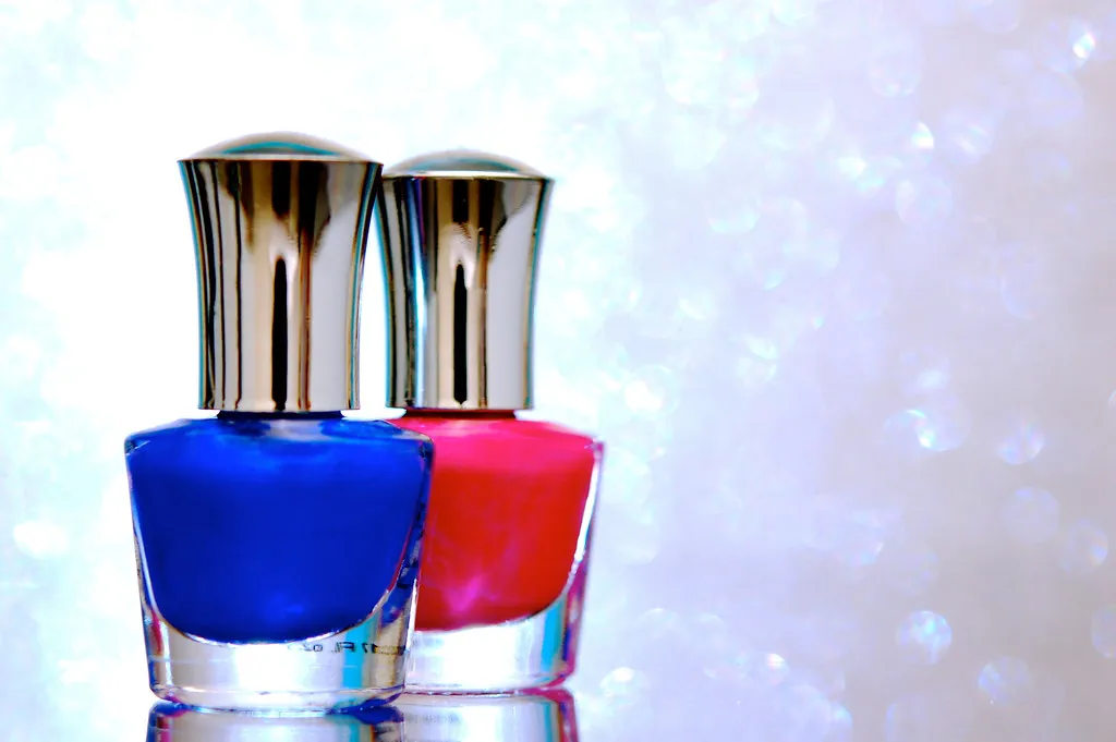 Frascos de esmalte azul cobalto y rojo sobre fondo brillante
